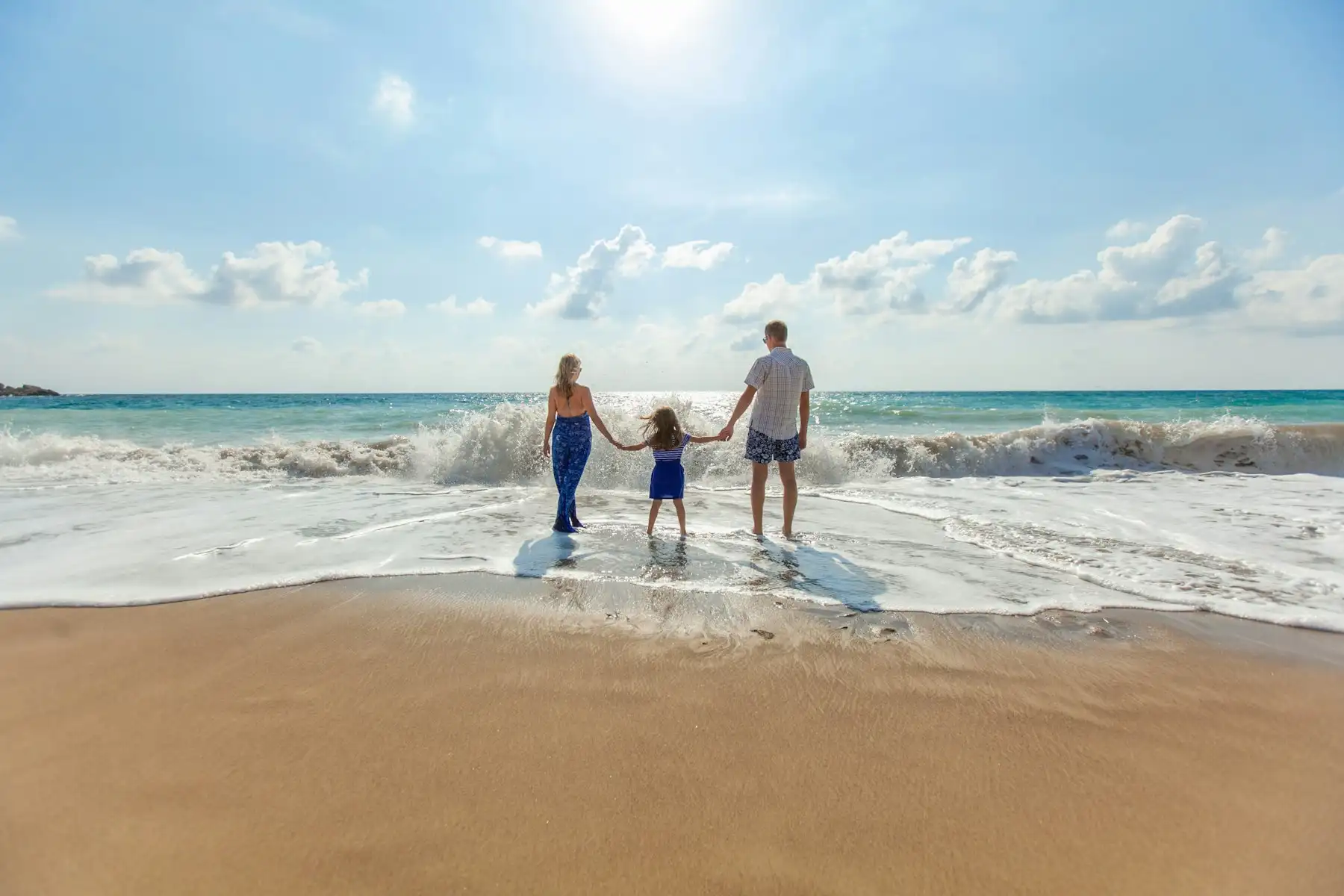 Família de mãos dadas caminhando na praia